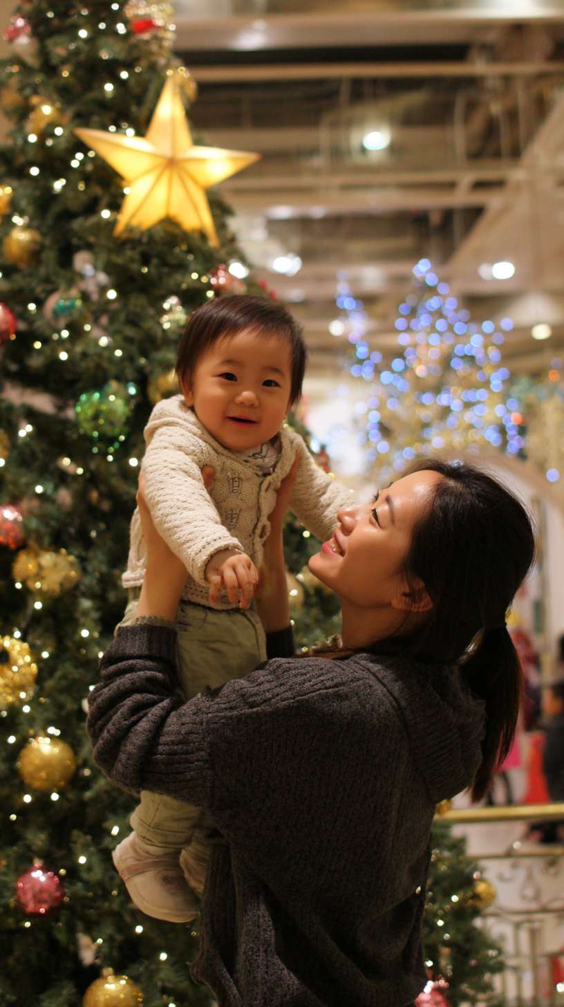 2圣诞树顶挂星星，妈妈托举孩子，树身缠绕彩灯，地面有未挂的袜子装饰，镜头从下往上推，温馨写实风欧美家庭 --ar 9:16 --v 7 --stylize 100 --fast --no 水印