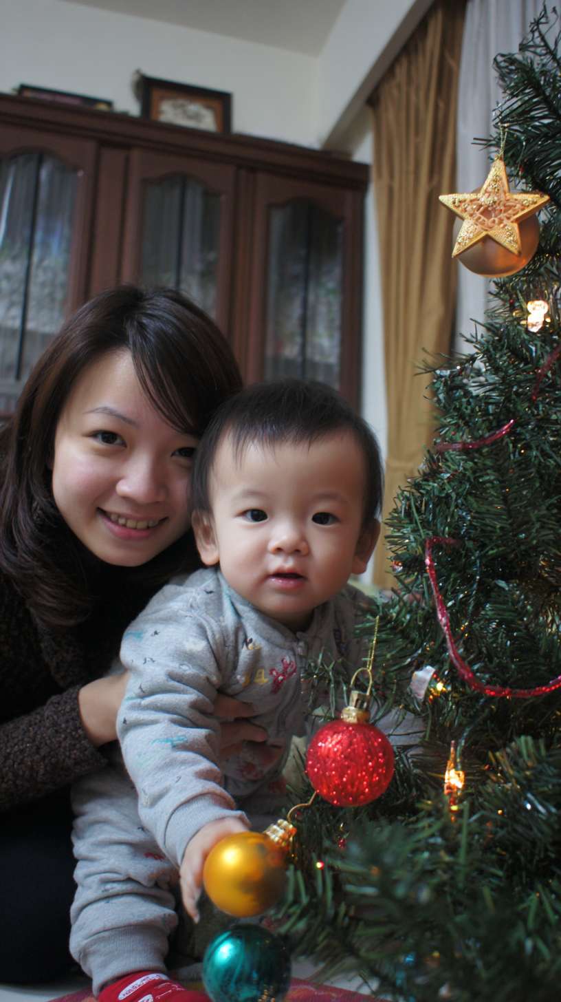 2圣诞树顶挂星星，妈妈托举孩子，树身缠绕彩灯，地面有未挂的袜子装饰，镜头从下往上推，温馨写实风欧美家庭 --ar 9:16 --v 7 --stylize 100 --fast --no 水印