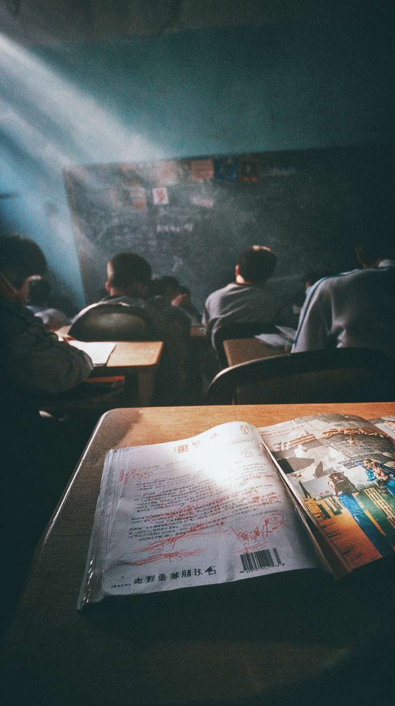 快速交叉剪辑：1) 游戏屏幕中，充满“侠义”字样的高度模糊化战斗画面；2) 现实中的课桌桌面，出现用红笔涂鸦的暴力图案（镜头快速带过，部分像素化处理）。一只手将一本《法律基础》推入画面阴影中。最后是一个仰视镜头：几个模糊的、具有威胁感的学生身影轮廓，挡住阳光，营造压抑感。 --ar 9:16 --v 7 --stylize 100 --fast --no 水印