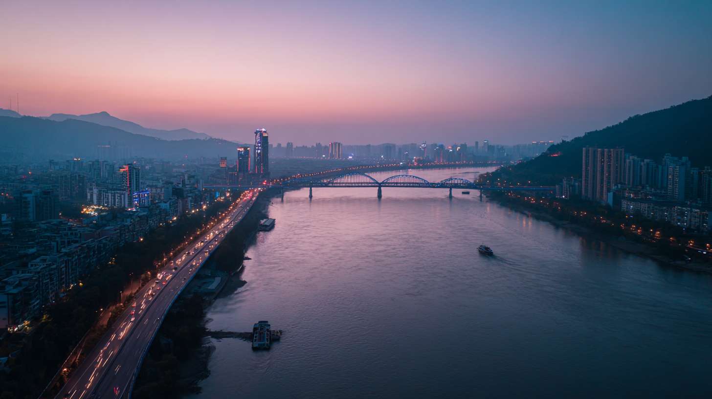 繁华都市白天转黄昏，车流在桥梁上平稳移动，船只缓缓驶过河面，两岸建筑灯光逐渐亮起，航拍镜头缓缓前移，展现城市昼夜交替的活力。 --ar 16:9 --v 7 --stylize 100 --fast --no 水印